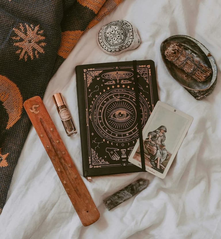 Tarot journal, sage, and crystals arranged for ritual work — tools used by Amber, Queen of Wands.