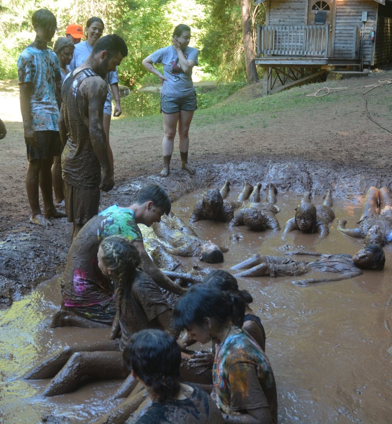 a group of people standing around a muddy puddle