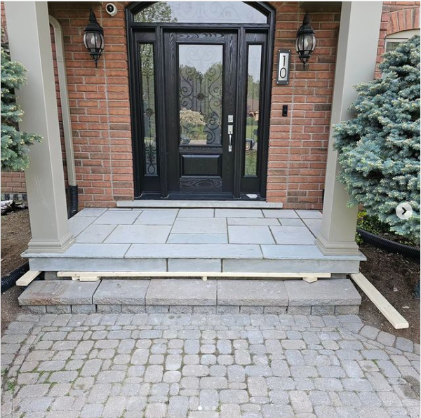 a front door with a black door and a brick wall