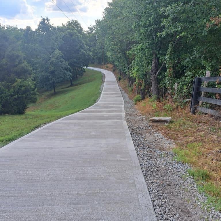 a paved road with a wooden fence and a bench