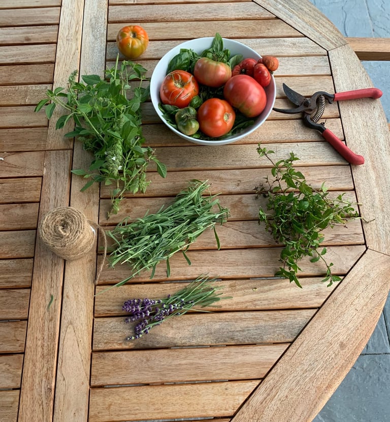 Heirloom tomatoes, fresh herbs, gardening tools and twine on an outdoor wood table