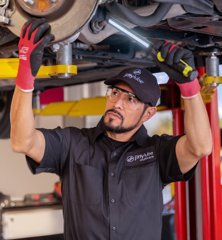 Technician inspecting a car's undercarriage.