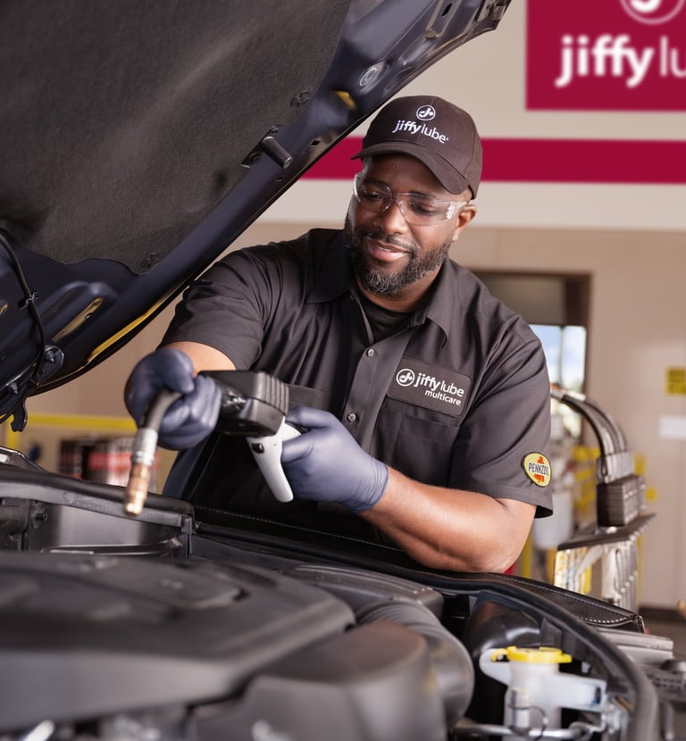 Technician working under the hood of a car.