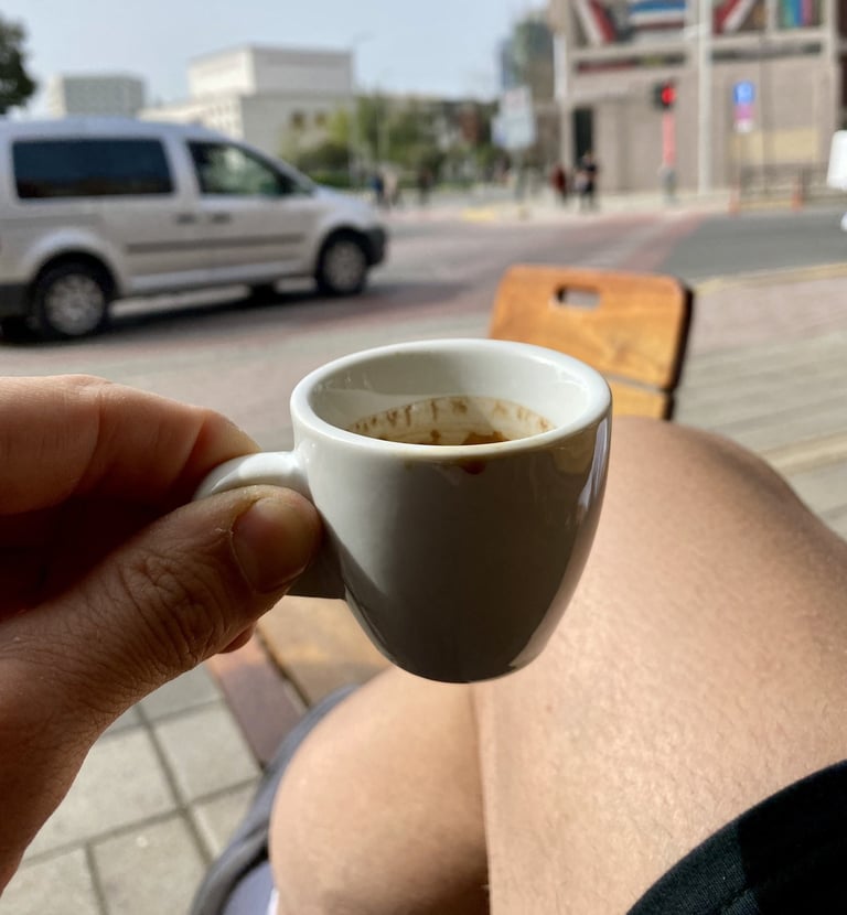 Persona disfrutando un café espresso en una terraza de Tirana, Albania, con vista urbana y ambiente 