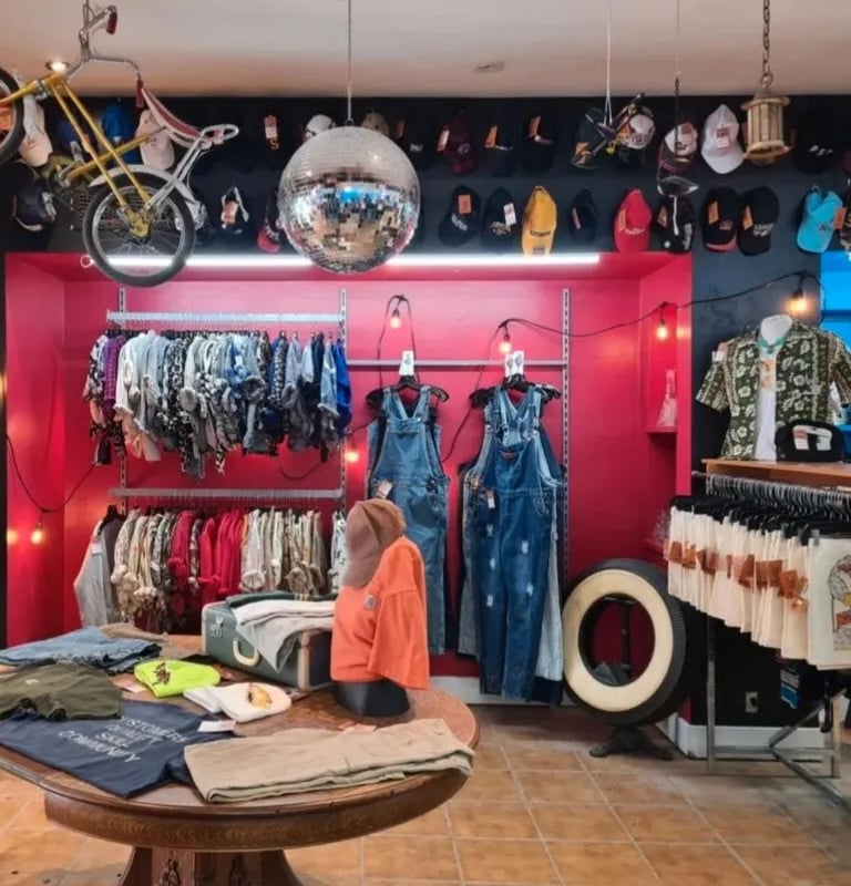 Sélection de vêtements vintage et mode rétro façon friperie exposée sur des portants industriels.