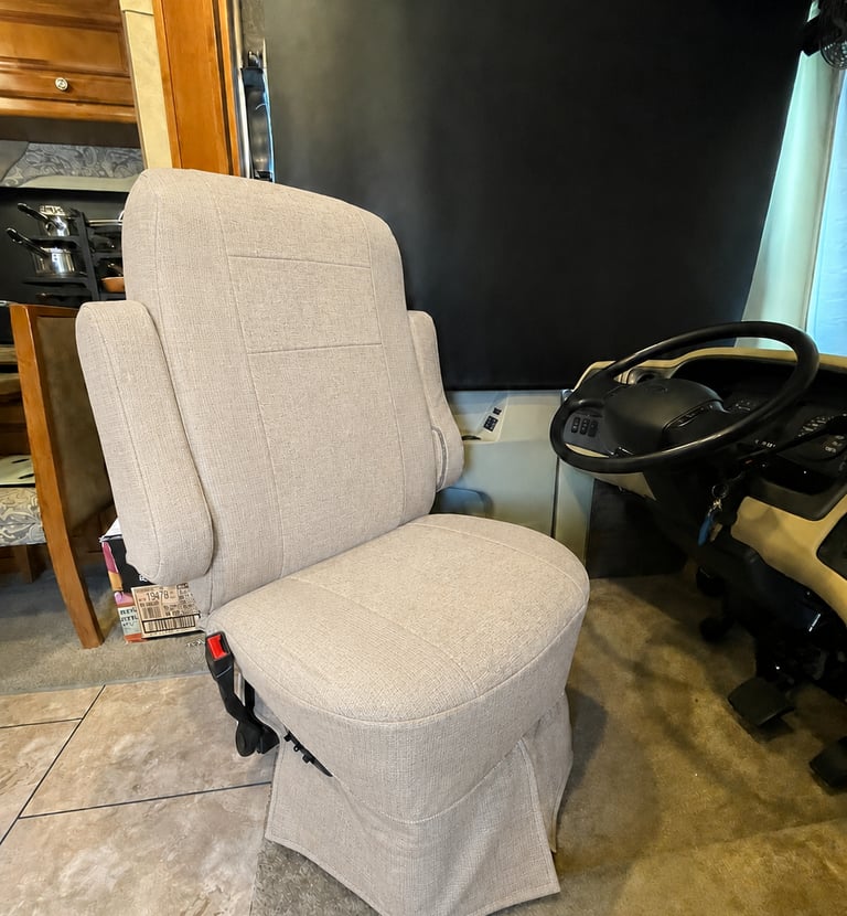 Light beige fabric upholstery on a swivel RV captain chair inside a motorhome cockpit.
