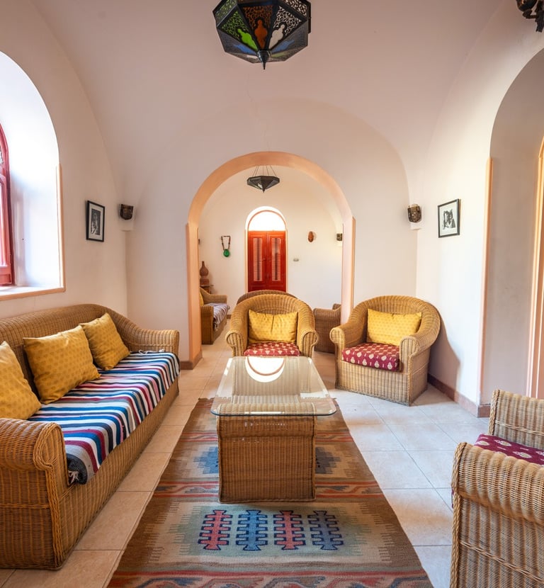 Villa al diwan living room featuring wicker furniture, arched doorways, and a colorful woven rug.