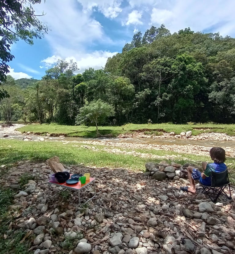 Família acampando na beira do rio em meio à natureza
