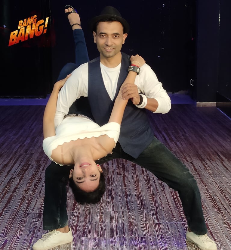 Professional dance partners performing an acrobatic dip pose in a studio for Bang Bang choreography.