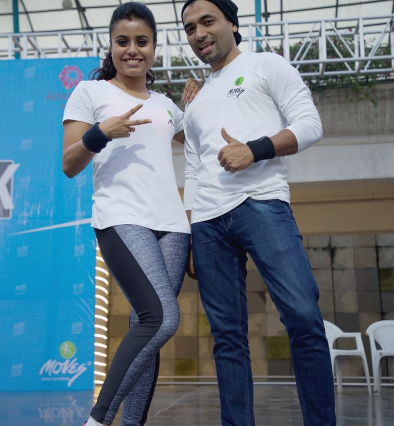 Smiling man and woman in white athletic shirts posing at an outdoor fitness event.