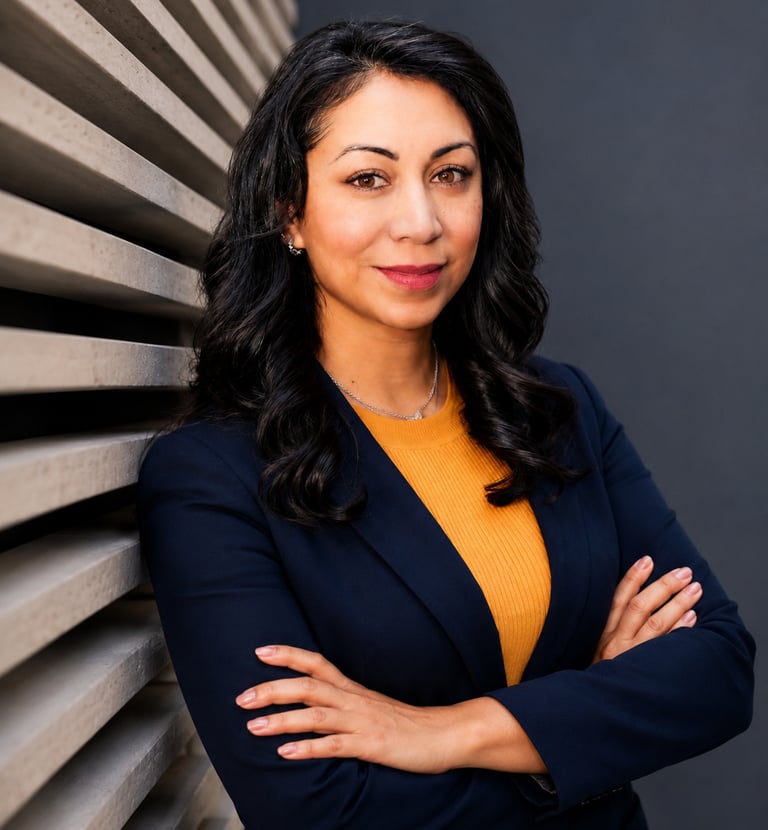 Professional corporate headshot of a business woman in a navy blazer against a modern backdrop.