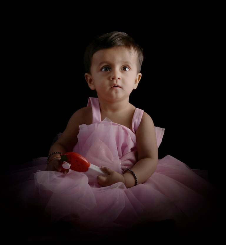 Baby girl in a pink dress holding a toy during a portrait session. Milestone Photography