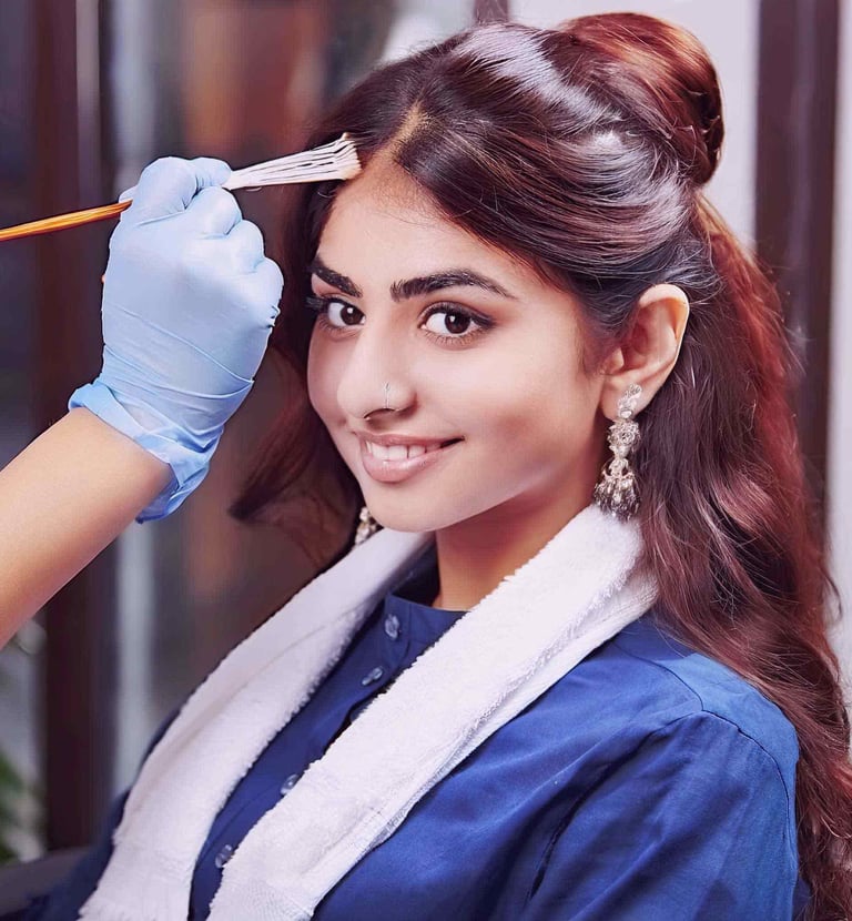 a woman in a blue shirt is getting her hair roots touched up by colors
