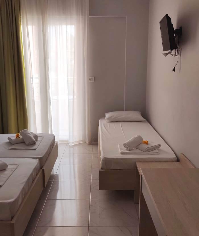 a triple bedroom with three beds and a television