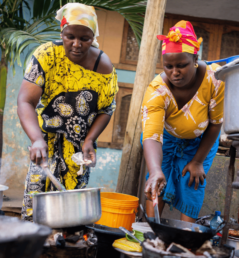 two women cooking in a kitchen with pots and pans