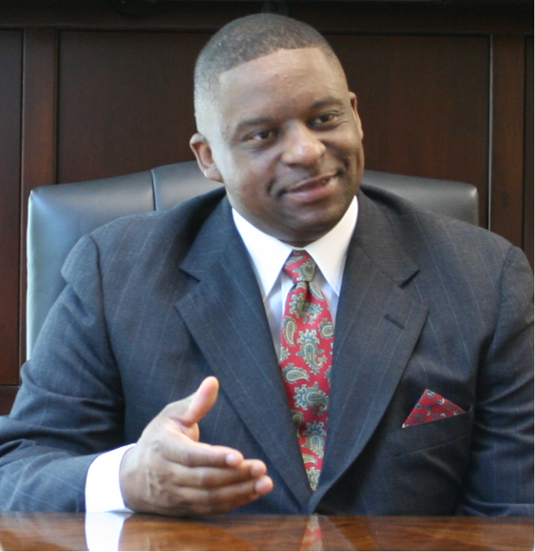 Mark T Stewart in a suit and tie sitting at a desk