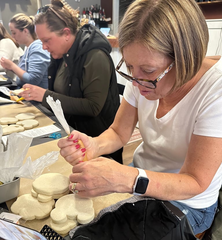a woman in glasses and a white shirt is decorating sugar cookie