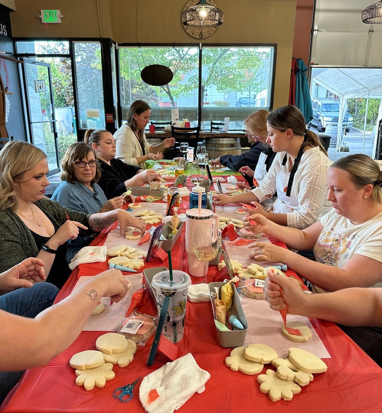 a group of people sitting at a table decorating cookies