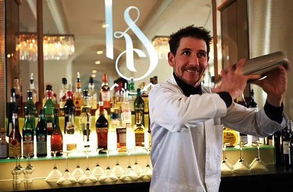 a man in a white shirt is holding a shaking a cocktail shaker