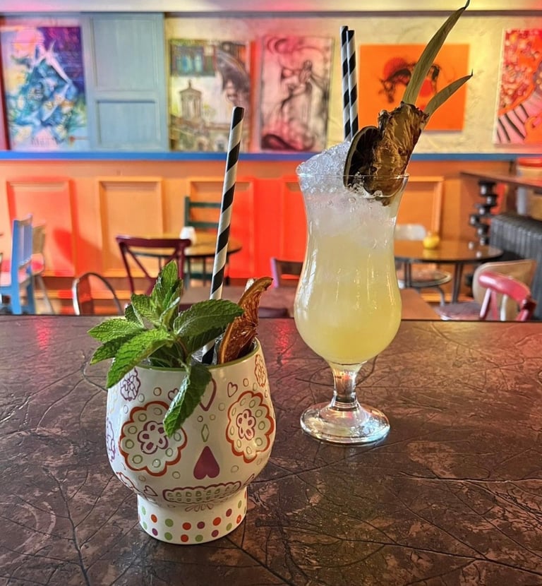 a couple of styled cocktail drinks in fancy glasses with mint leaves
