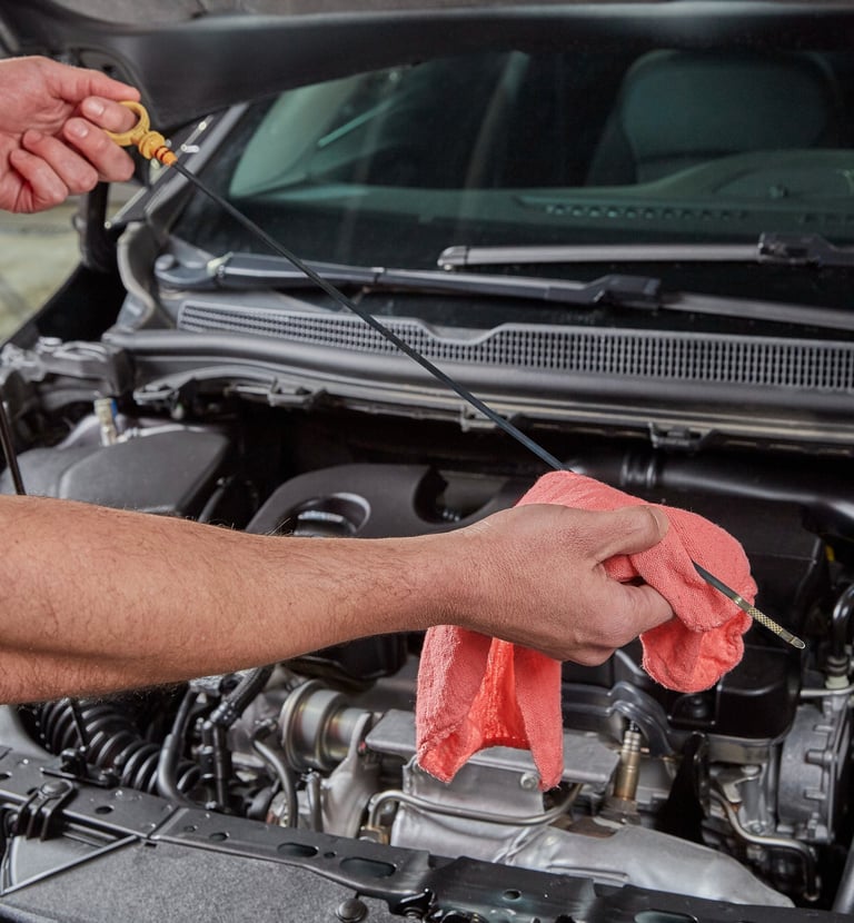 Big O Tires employee checking engine oil