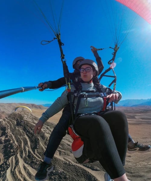 A young woman flying in a paraglider, enjoying the experience.