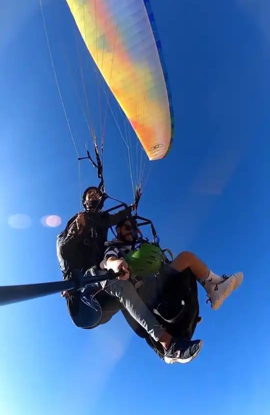 A pilot flying with a passenger, both enjoying the paraglide ride