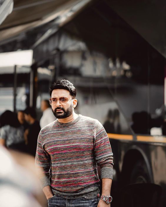 a man in a striped sweater and jeans standing in front of a food truck