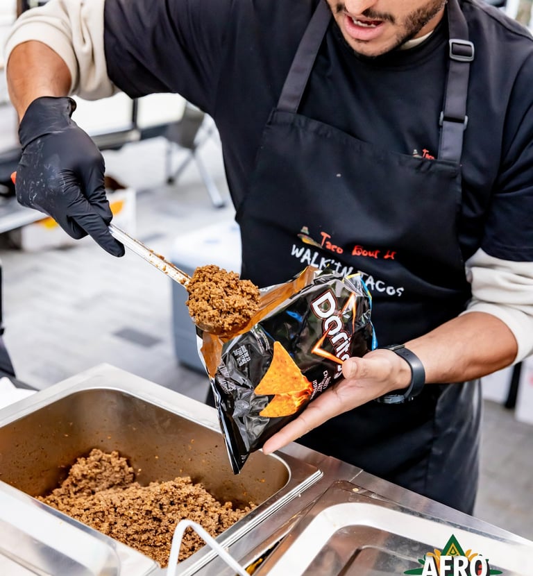 Chef preparing a walking taco with seasoned ground beef and Doritos chips at Afro Fiesta Festival.