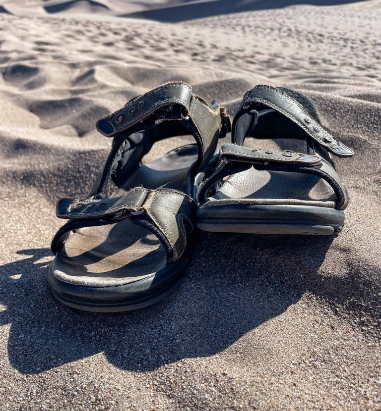 a pair of sandals that are on the sand