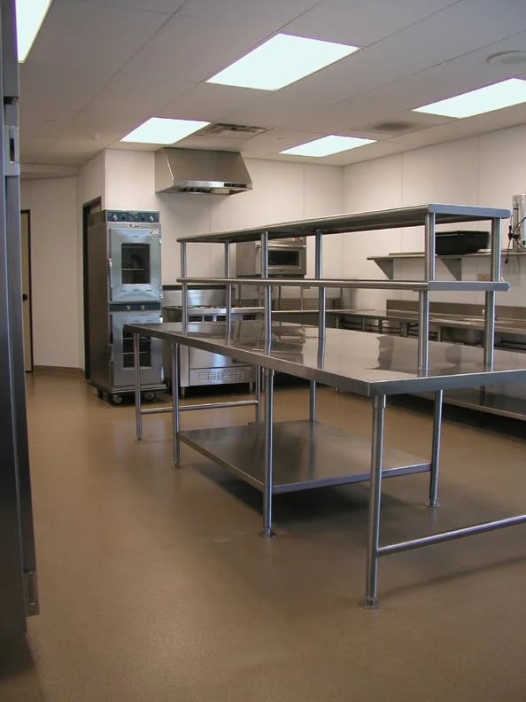 Commercial kitchen setup with tiered stainless steel prep benches and industrial equipment, from the About SSB team.
