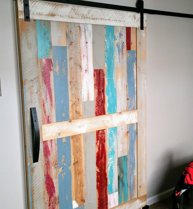 reclaimed wood antique looking custom closet barn door painted in reds, blues, and whites. Colorado Springs remodel.