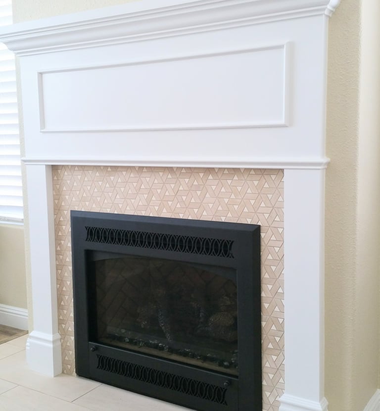 black fireplace with mixed media surround of triangular tan tile work surrounded by painted white wood work and mantle.