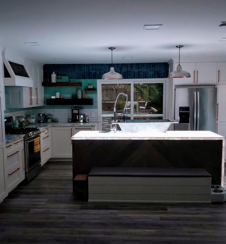 Colorado Springs. Remodeled kitchen with waterfall edge island lit up from underlaid LED lights. 