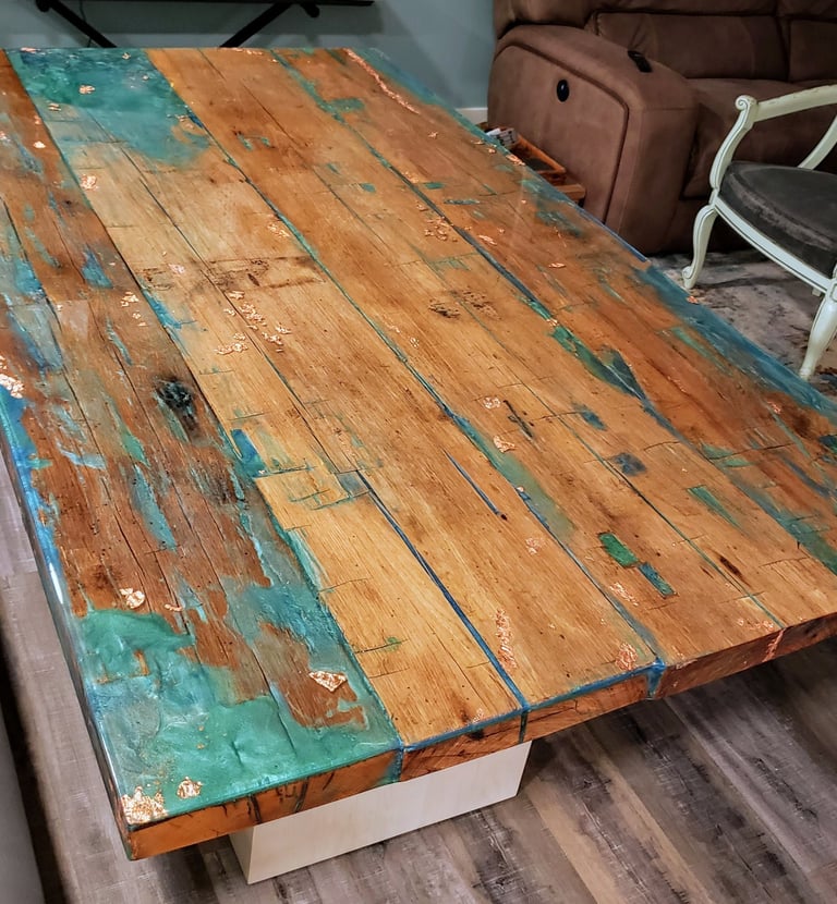 Custom handmade epoxy resin and reclaimed wood dining table.  natural wood colors with spots of blue green epoxy and gold. 