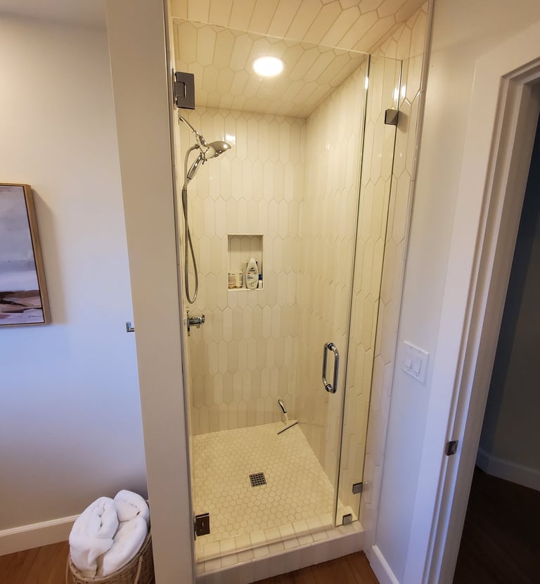 Remodeled shower with white shade tiles on walls and ceiling.  glass door and cut in shelf for shampoo. Colorado Springs.