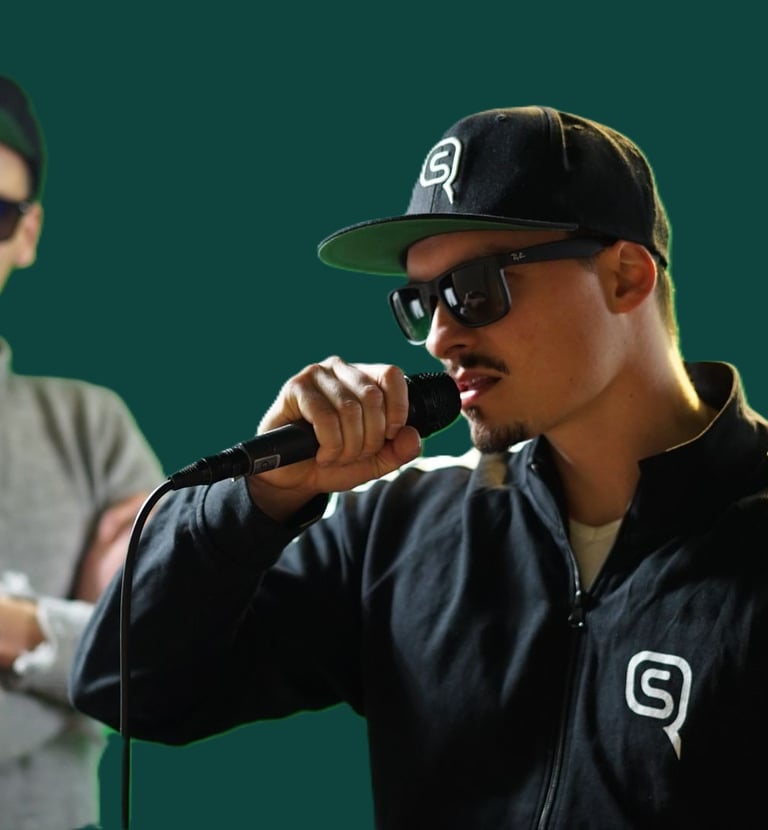 a man in a dark blue jacket with a black cap and sunglasses is holding a microphone