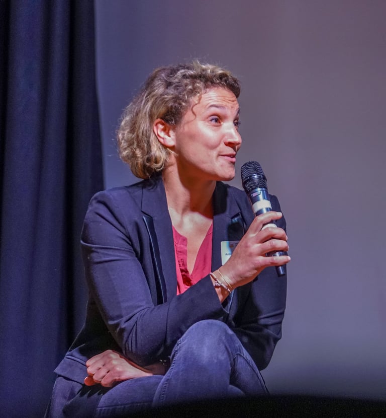 Femme avec un micro assise qui parle pendant une conférence