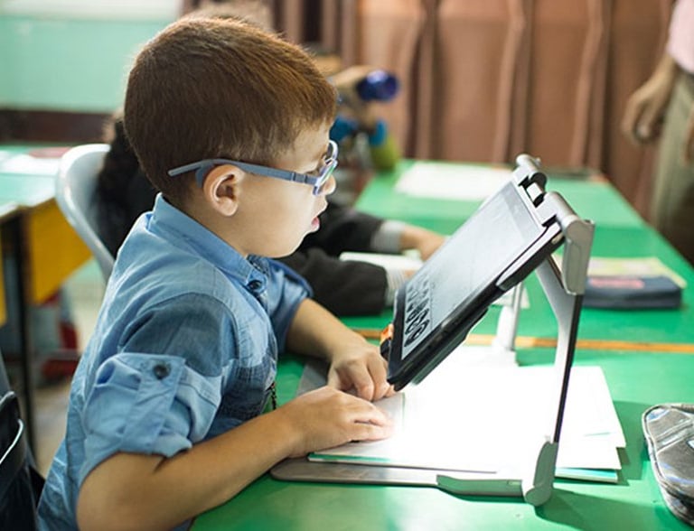 Legally blind child with low vision using assistive technology, screen reader, video magnifier for vision impairment