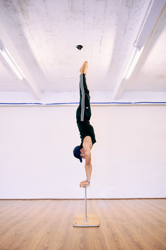 Man voert een rechte handstand uit op canes bij De Polecats Fabriek in Gent