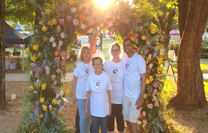 a group of people standing in front of a flower arch
