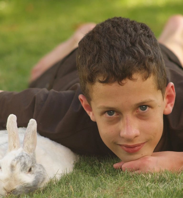 un garçon avec un lapin blanc dans l'herbe