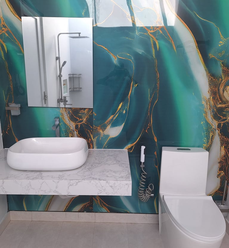 Modern bathroom featuring a white vessel sink, marble countertop, and emerald green marble effect wall panels.