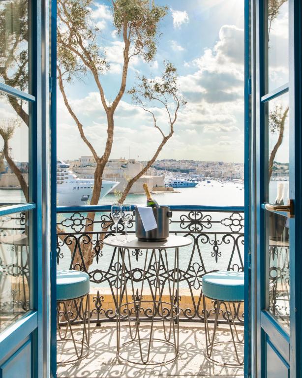 Luxury balcony view of Valletta harbor in Malta with champagne and blue shutters.