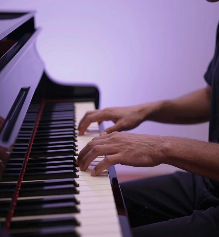 An action shot of hands playing a piano under a pale lavender spotlight. The aesthetic is moody and soulful, reflecting a live musical performance. Professional lighting, sharp detail on the keys.