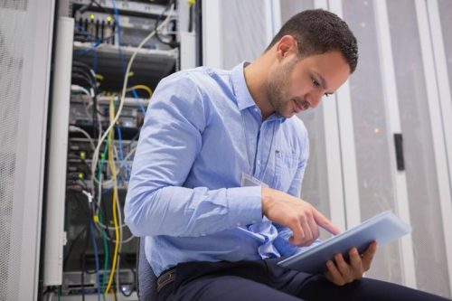 a man in a blue shirt is holding a tablet computer and looking at a tablet