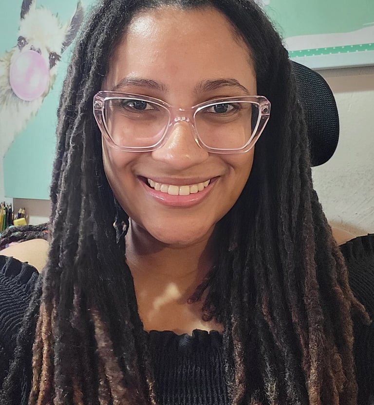 Briele, mulher negra sorrindo com cabelo longo endredado, usando óculos de armação transprente