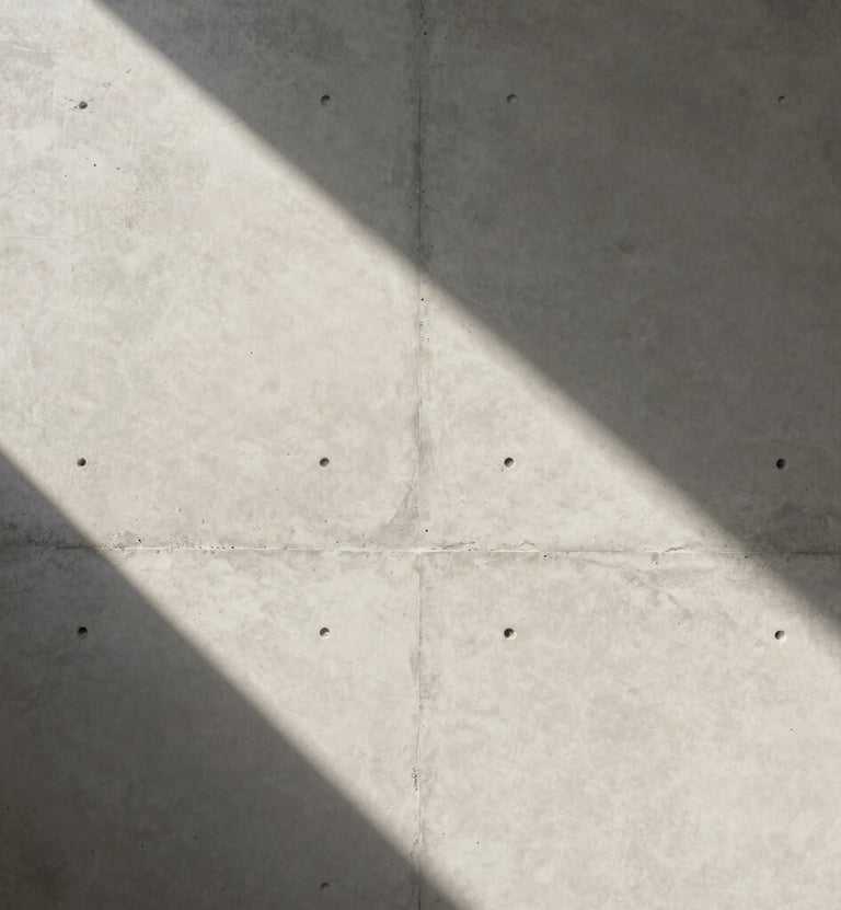 A minimalist detail of a textured concrete wall hit by a sharp sliver of morning light in a Global / Contemporary Art setting. Neutral off-white and soft gray tones. High-end editorial photography style with a focus on geometric shadow.