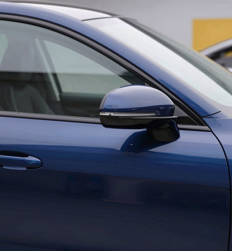 Detailed 'After' shot of a luxury car door, perfectly smooth with zero dents, reflecting a clean workshop environment. Professional lighting highlighting the deep blue paint. Style: High-end automotive photography with brand colors #0A1E3C and #E7C670 subtly present in the workshop background.