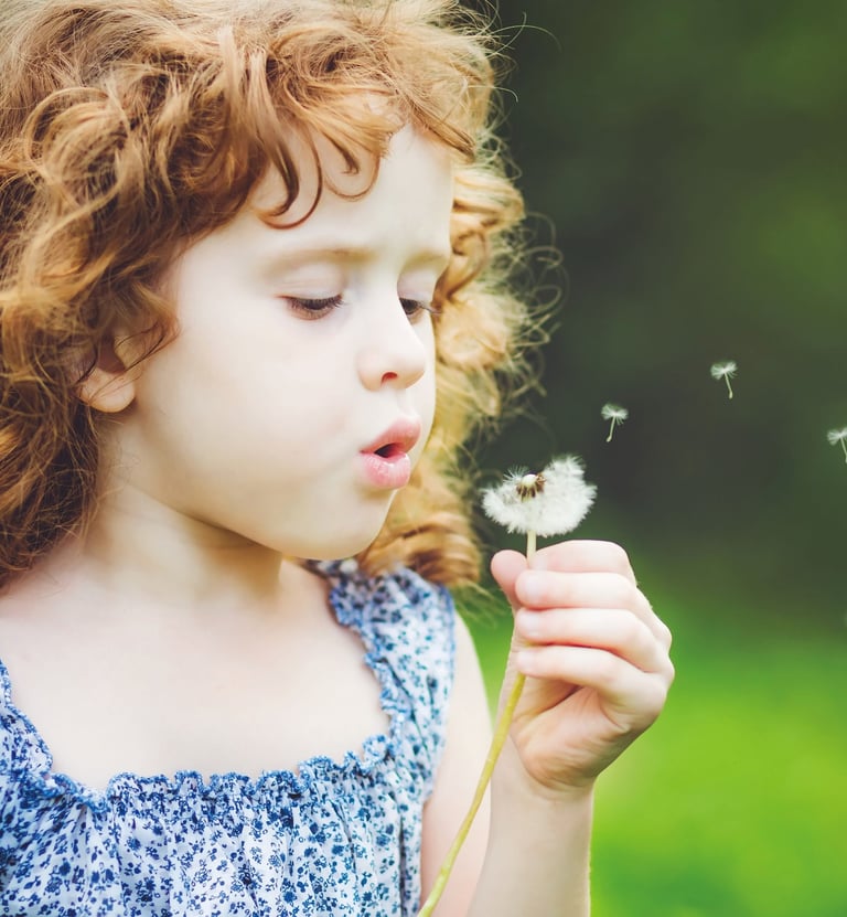 girl blowing dandelion